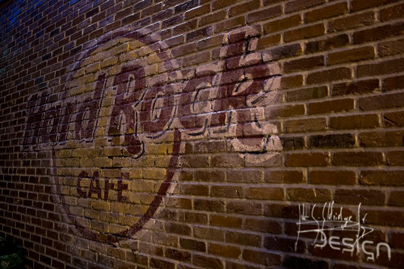 The venue's logo painted on the brick wall — a room detail that dates and places the whole set.