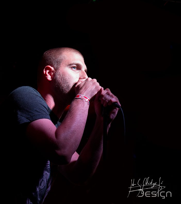 Vocalist under magenta, cropped tight enough that the colour becomes the subject.
