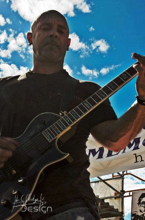 Hempfest, Seattle — guitarist from below against open sky, which is the one lighting condition you cannot negotiate with.
