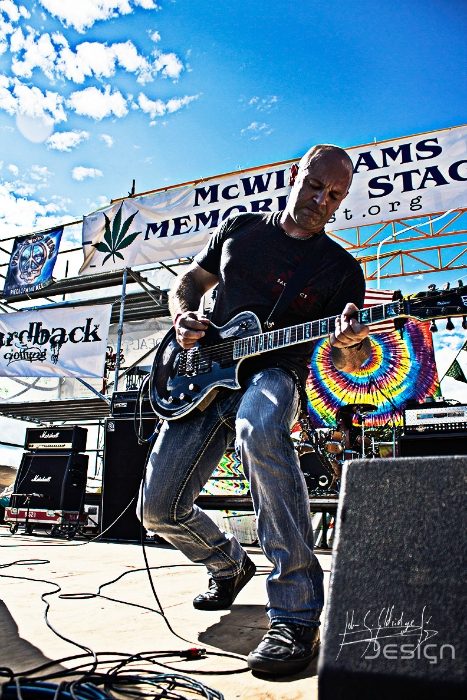 Wider on the festival stage, banners and daylight competing for the background.