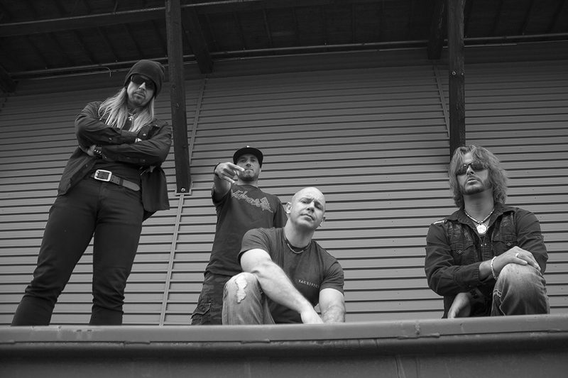 Band portrait against the venue's roll-up loading door, black and white.