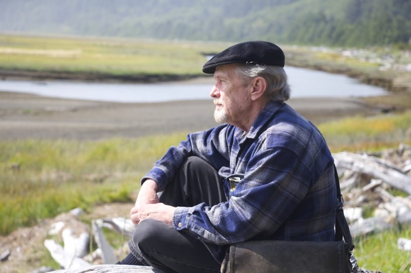 Author photograph by Richard Gerber — my father on driftwood above a tidal marsh in a flat cap and plaid shirt, the portrait that runs on the back cover and sets the book's only warm note